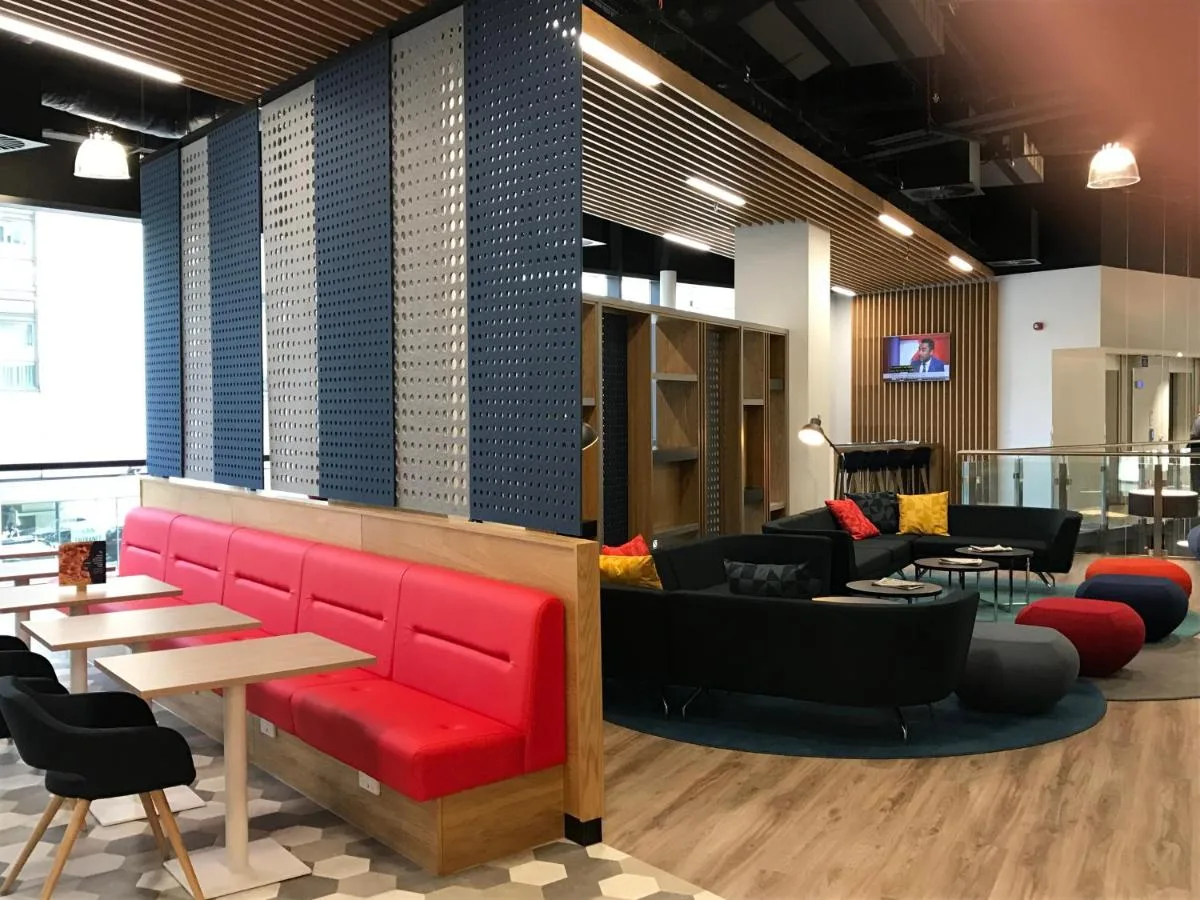 a lobby with a red couch and tables and chairs at Holiday Inn Express - Birmingham - City Centre by IHG near Brindleyplace